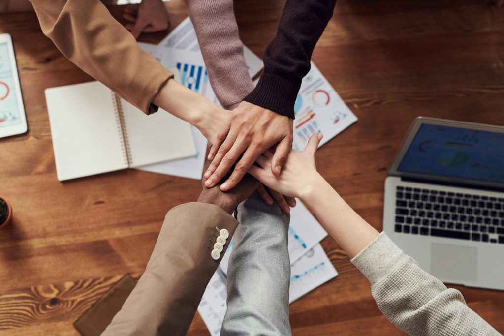 Des professionnels de divers horizons se réunissent pour travailler en équipe autour d'une table en bois, avec des ordinateurs portables et des documents.