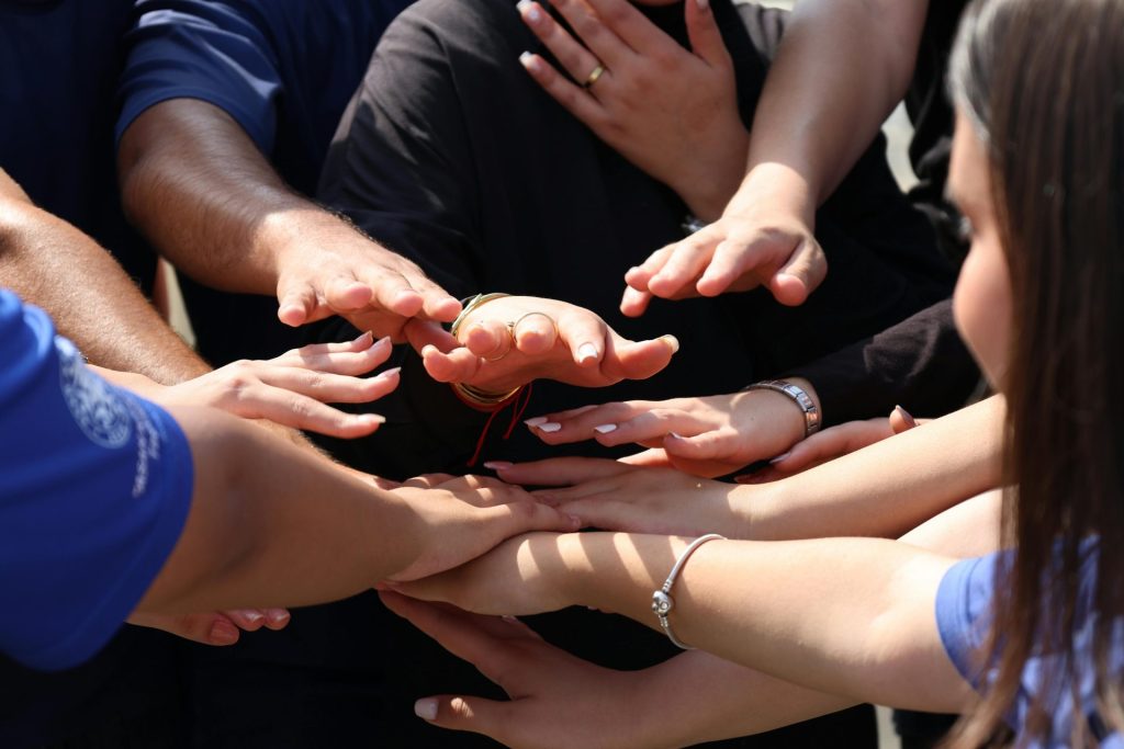 Des mains jointes formant un cercle, symbolisant l'unité, le travail d'équipe et l'esprit communautaire.