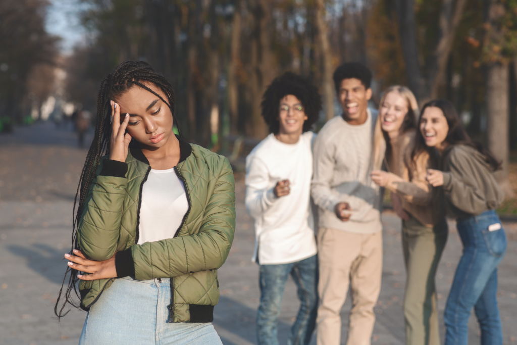 Jeune femme semblant préoccupée, avec un groupe de jeunes en arrière-plan dans un cadre urbain.
